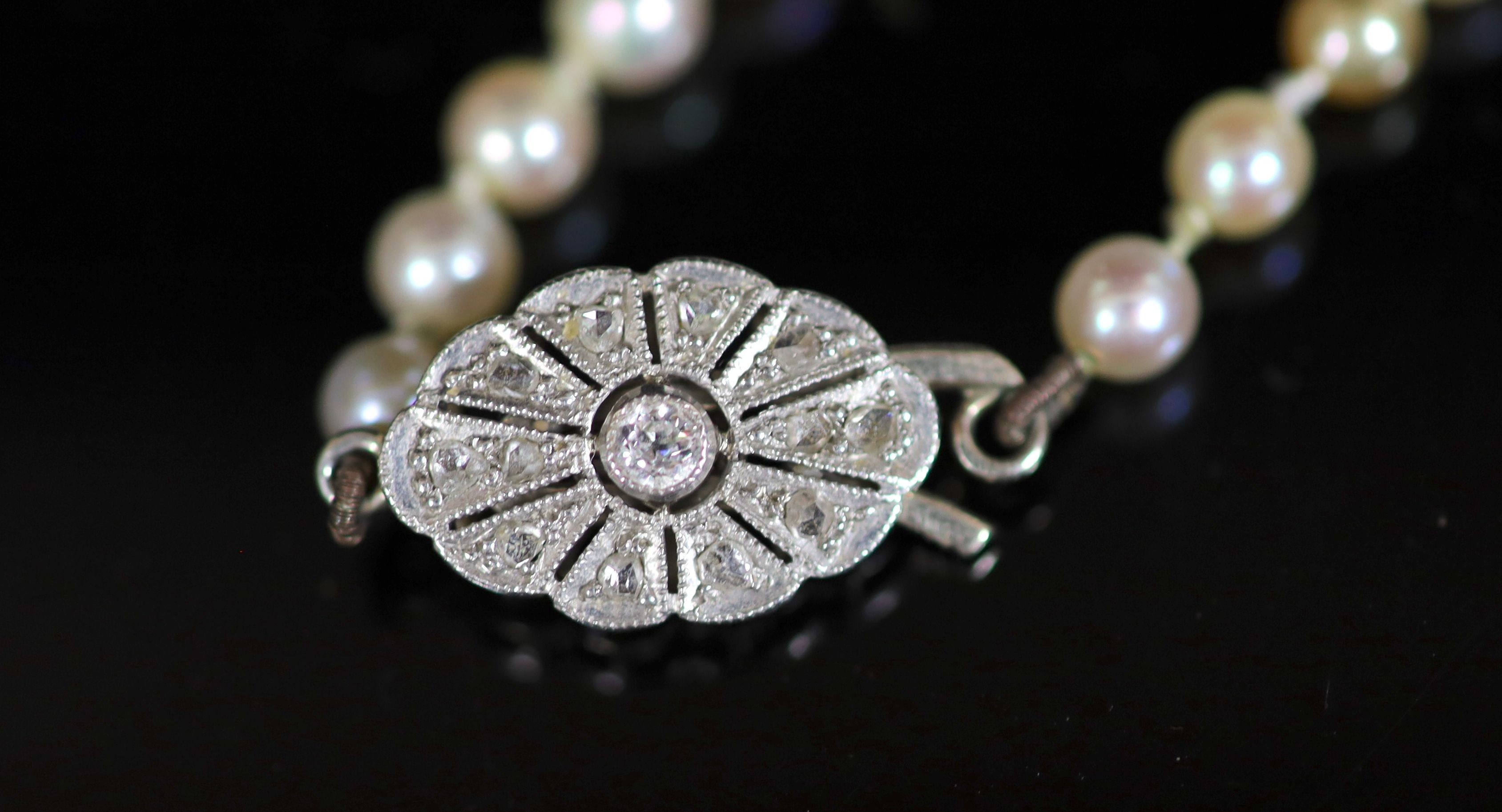 An early 20th century graduated pearl necklace, with platinum and millegrain set diamond clasp